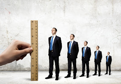 a giant ruler is held next to line-up of businessmen to measure their growth