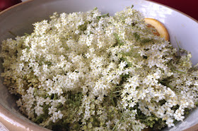 Large bowl filled with elderflower heads and citrus fruit