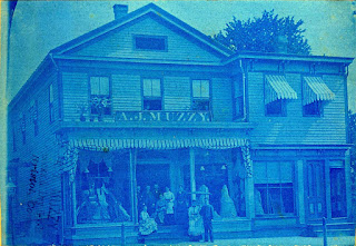 19th century store in blue tint with staff on steps in front. Photo probably taken 1910 or earlier.
