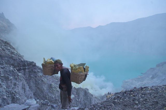 Seorang penambang belerang Kawah Ijen sedang memikul keranjang berisi belerang