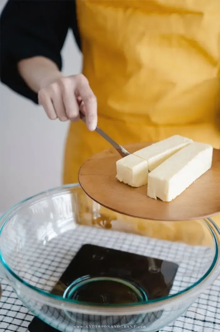Adding sticks of butter to a clear glass bowl