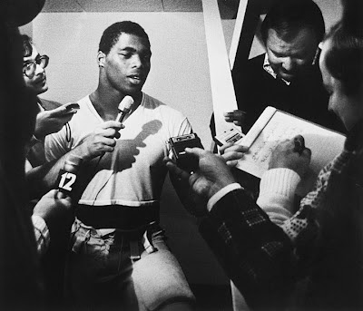 Herschel Walker surrounded by reporters in the locker room