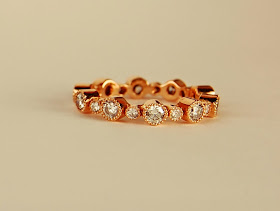 18k pink toned metal ring with large and small diamonds alternating in bezel settings with milgraine