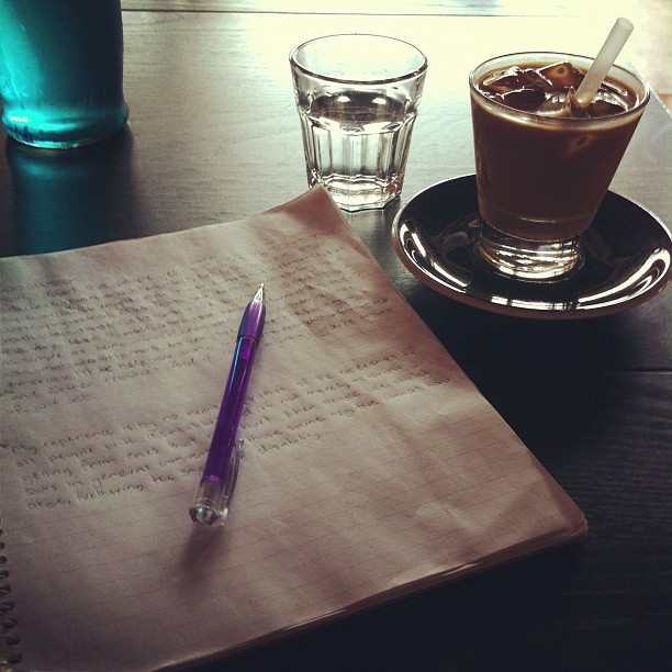 Photo of my study notebook and an iced coffee on a table at a local café.