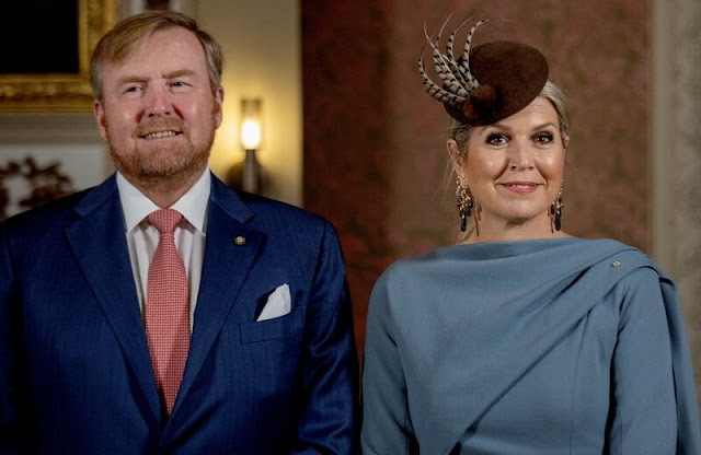Queen Maxima wore a sky blue silk cape dress by Natan. She wore a wool camel coat. Ole Lynggaard gipsy earrings