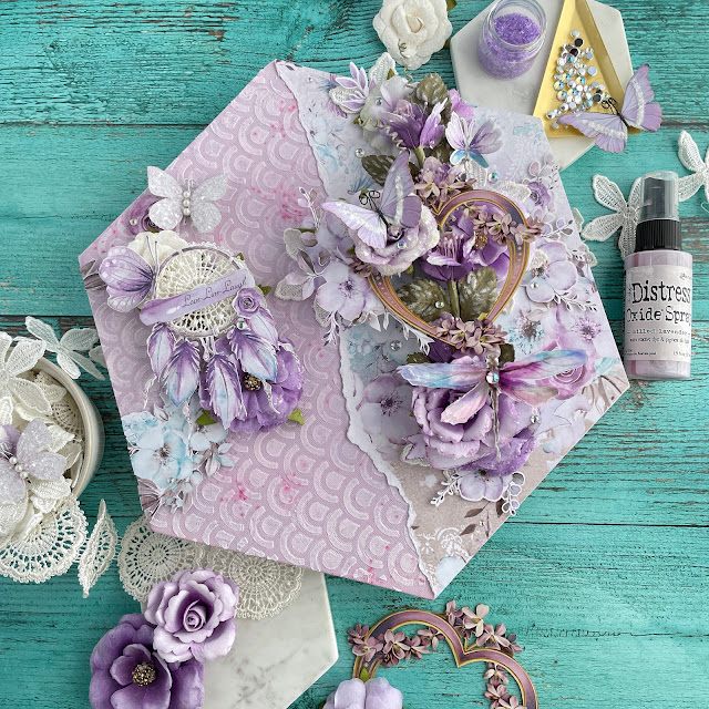 Purple Haze mixed media canvas created with: Prima aquarelle dreams paper, flowers, ephemera, acetate, lace, Reneabouquets butterflies, printed chipboard heart; Tim Holtz distress oxide milled lavender; Pinkfresh clear drops iridescent