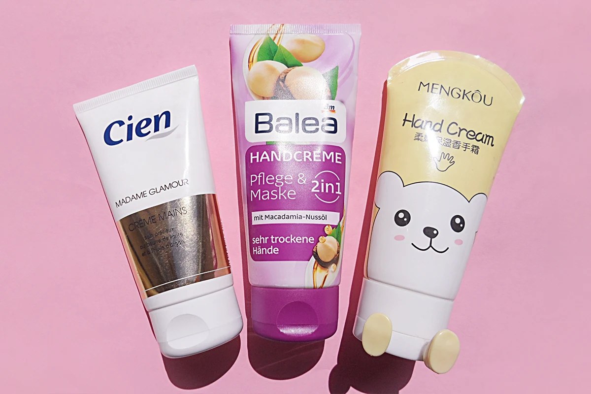 close-up shot of three hand creams laying on top of a pink table