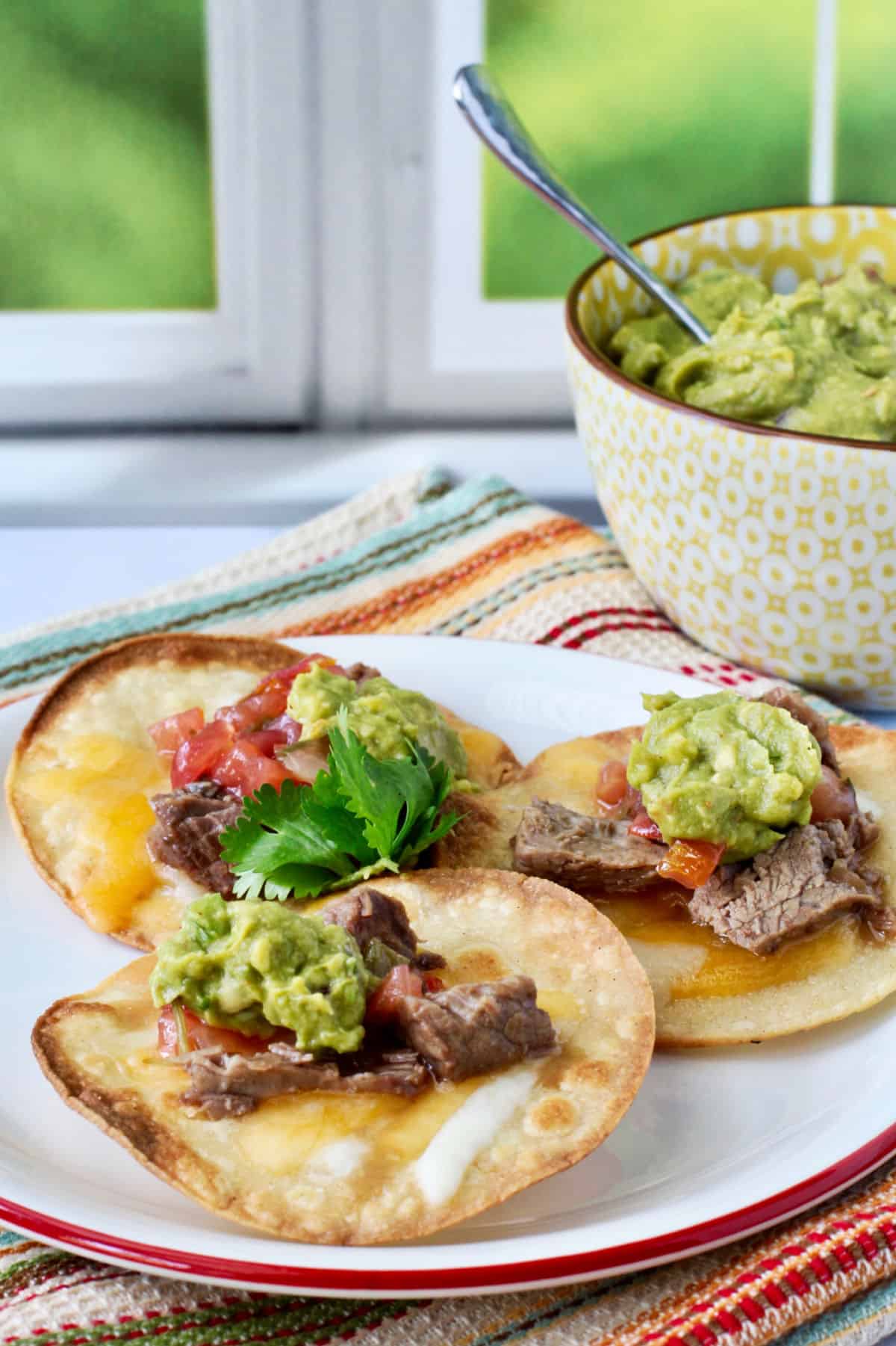 Short rib mini tostadas on a plate with a red rim.