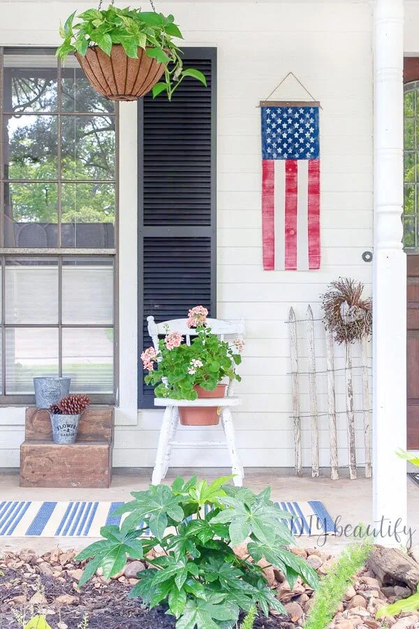 flag banner on front porch with shutters, flowers