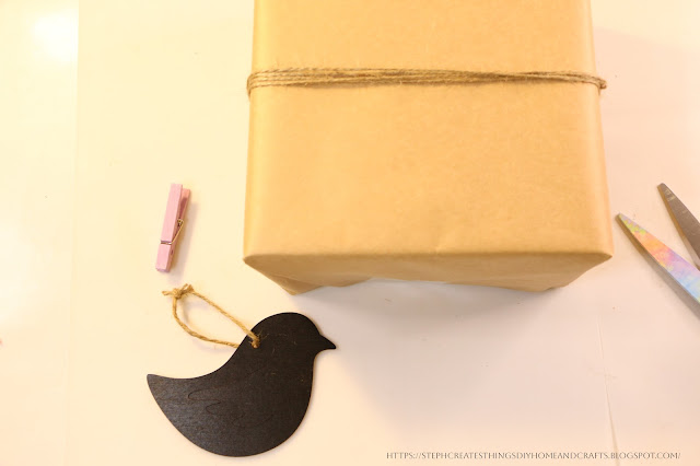 wrapped gift box with twine wrapped around with craft bird, and craft clothespin