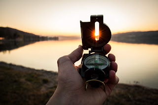 Hand with a compass, directed to the sun, sunset