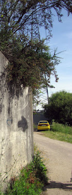 uma seta preta pintada num muro de pedra e um carro amarelo ao fundo