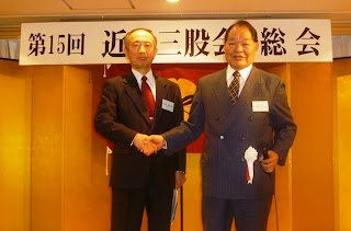 野崎博美前会長と小牧憲一郎新会長の固い握手
