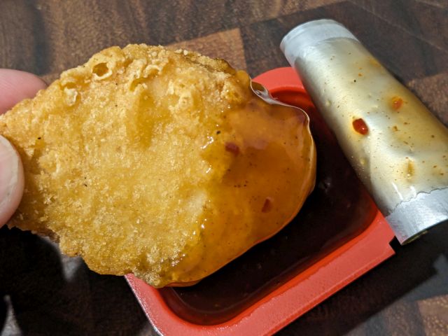 A close-up of a Chicken McNugget dipped in McDonald's WcDonald's Sauce.