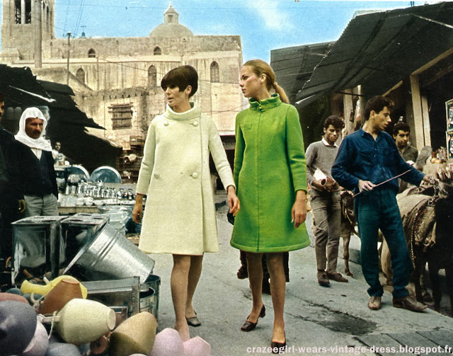 1960 1966 60s 60's 1960's fashion pierre cardin andre courreges sixties années 60 space age mode Du désert du Neguev à Saint~Jean~d'Acre, de la Mer Morte à Tel-Aviv, Paris, le mois dernier, était à l'honneur : Pierre Cardin présentait sa collection aux Israéliens. Première étape ; le musée d'Israël à Jérusalem où, sous la présidence de Mme Eshkol, femme du Premier Ministre, les " cosmonettes " ont défilé devant le dôme étincelant du " Sanctuaire du Livre ", Fêté par tout , le grand couturier a découvert ce tout jeune pays vieux de 4000 ans avec autant d'enthousiasme que celui-ci mit à l'accueillir.   A vous de les applaudir tous deux dans les pages qui suivent .Dans ce pays ultra-moderne, on rencontre à chaque pas , les témoins d'un riche passé. A Jaffa , un des plus vieux ports du monde, la boîte de nuit à la mode - Le "Hammam" - s'ouvre sur un antique portique .     Ci-dessous ,  une chasuble “ cosmocorps" en lainage, avec un pull-over à col roulé .A Césarée , un acqueduc romain longe la plage , joyau de la "Côte d'Azur" israelienne .     Ci dessous  , cosmocorps à carreaux .Et, au fin fond du désert du Neguev , surgissent les légendaires mines du roi Salomon dont on extrait encore le cuivre .  Ci dessous , deux cosmocorps en lainage Le somptueux hotel du Golf , construit par le baron Edmond de Rothschild dans ce grand centre de villégiature qu'est Césarée.  Tailleur en lainage capitonné , jupe froncée , veste à col officier.Ci dessous , ensemble en lainage à carreaux ton sur ton .Partout en Israël se croisent l'Orient et l'Occident . En Galilée , dans la vieille ville de Nazareth , un souk oriental aux éventaires pittoresques .  Manteau blanc en lainage , évasé dans le bas , et manteau vert en gabardine , fermé par une broche dorée .and now my Cosmocorps . 