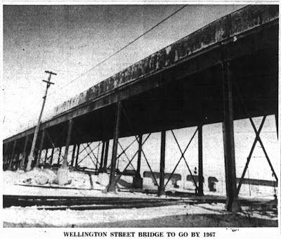 Newspaper clipping showing a photo from the ground level on the north-west side under the viaduct looking through its steel support legs to the rear of the City Centre building opposite, with the caption Wellington Street Bridge To Go By 1967.