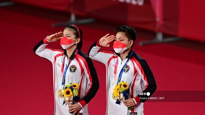 Atlet Indonesia Apriyani Rahayu (kanan) dan Greysia Polii Indonesia memberi hormat dengan medali emas bulu tangkis ganda putri mereka pada upacara selama Olimpiade Tokyo 2020 di Musashino Forest Sports Plaza di Tokyo pada 2 Agustus 2021. (Pedro PARDO / AFP)