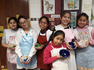 En la imagen se observa a seis alumnas con una vasija de color en la mano mostrando sus trabajos realizados en cerámica