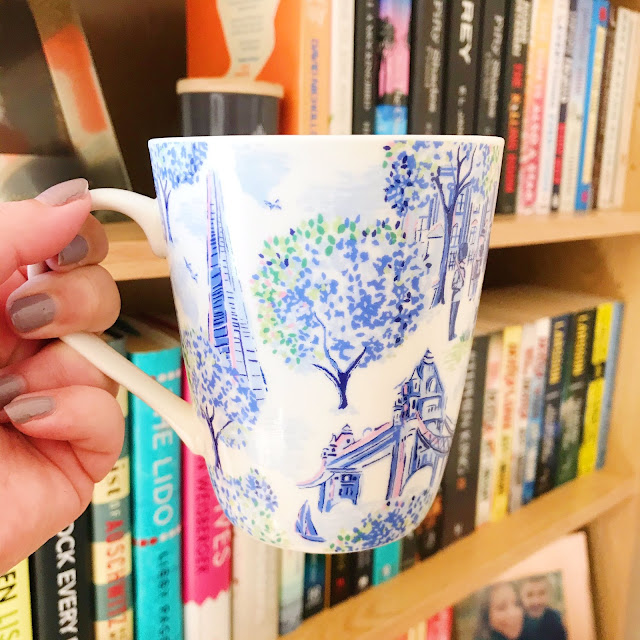 Cath Kidston mug held up in front of bookshelf