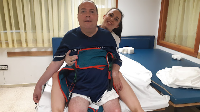Un hombre trabajando con la fisioterapeuta en una camilla, frente a un espejo