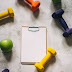 Colored dumbbells around fruits and clipboard