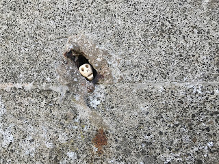 A close up photo of a small ceramic skull (Skulferatu 82) in a hole in the wall of the pill box.Photograph taken by Kevin Nosferatu for the Skulferatu Project.