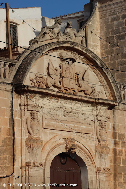 A dark wooden entrance door of a sandstone period property decorated with ornate stone carved dragons and figurines.