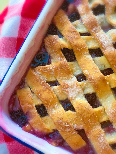 Blackberry Dumpling Cobbler, luscious, juicy blackberries layered between three layers of buttery, flaky crust with a rich syrup of butter, sugar, vanilla, and water poured over the whole cobbler.  This is where all the magic happens when the dough in the center forms pillows of tender dumplings.