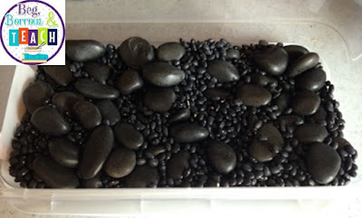 Setting up a sensory box with black beans and rocks from the Dollar Tree.