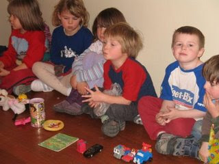 this image shows the children sitting in a line waiting to trade their items from the brown bag.