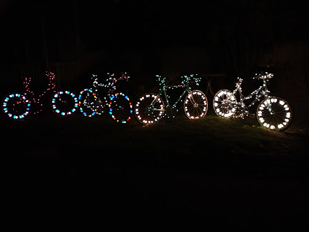 Bicycles lined up on a lawn with lights on their wheels