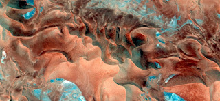 Effect on the dunes like the sea bottom in the African desert from the air, photographs of the Sahara desert bird's eye view, textures red sand as primitive forms of matter,