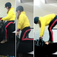 Three shots side by side of a vaulter wearing jodhpurs, riding boots, a yellow hoodie and a riding hat. She is on a mechanical horse (which cannot clearly be seen). In the first picture she is sitting, in the second she is kneeling and in the third she is standing but holding onto handles on a roller attached to the mechanical horse. She is looking down and smiling at a coach on the ground who is out of shot. She is definitely a beginner!