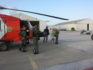 Stephanie and Coastie are at the front of the helicopter with photographer Jeremiah Khokhar and a Coast Guard member.