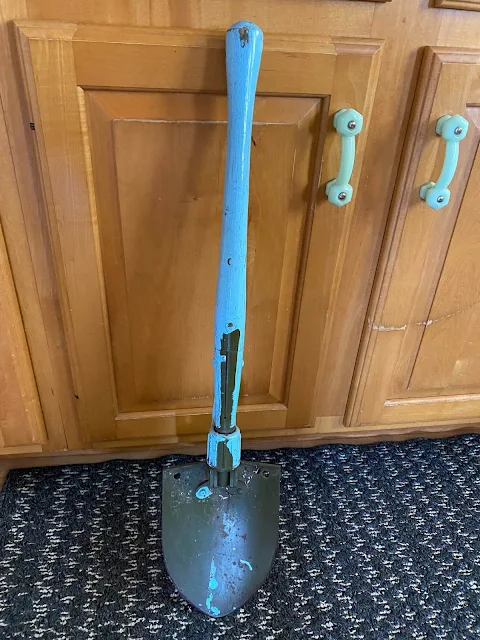 Photo of a camp style shovel with blue painted handle.