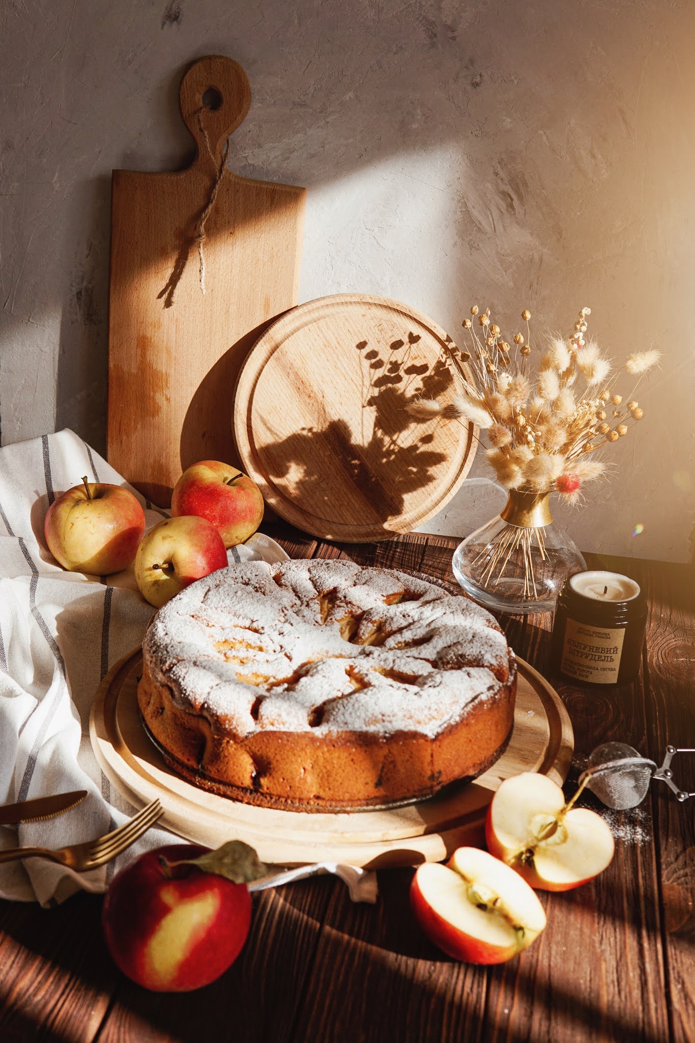 apple cake with icing sugar dust, surrounded by apples