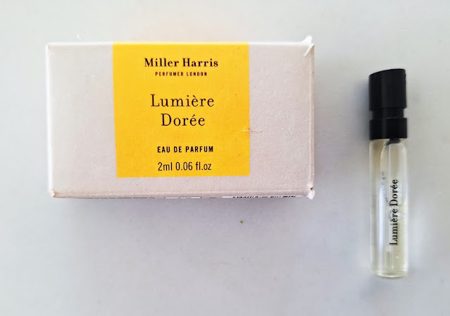 Bone & amber Miller Harris rectangular sample box with black upper & lowercase font & 2-ml sample vial with black font & top.