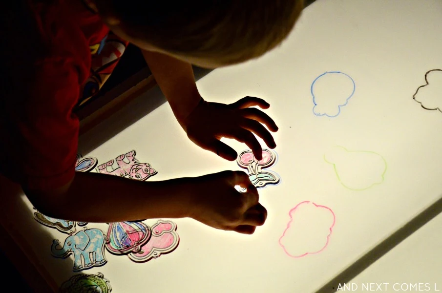 Creating a puzzle on the light table using dollar store sun catchers and dry erase markers from And Next Comes L