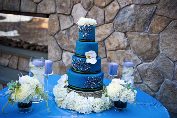 A beautiful rich blue wedding cake set over four tiers adorned with fresh