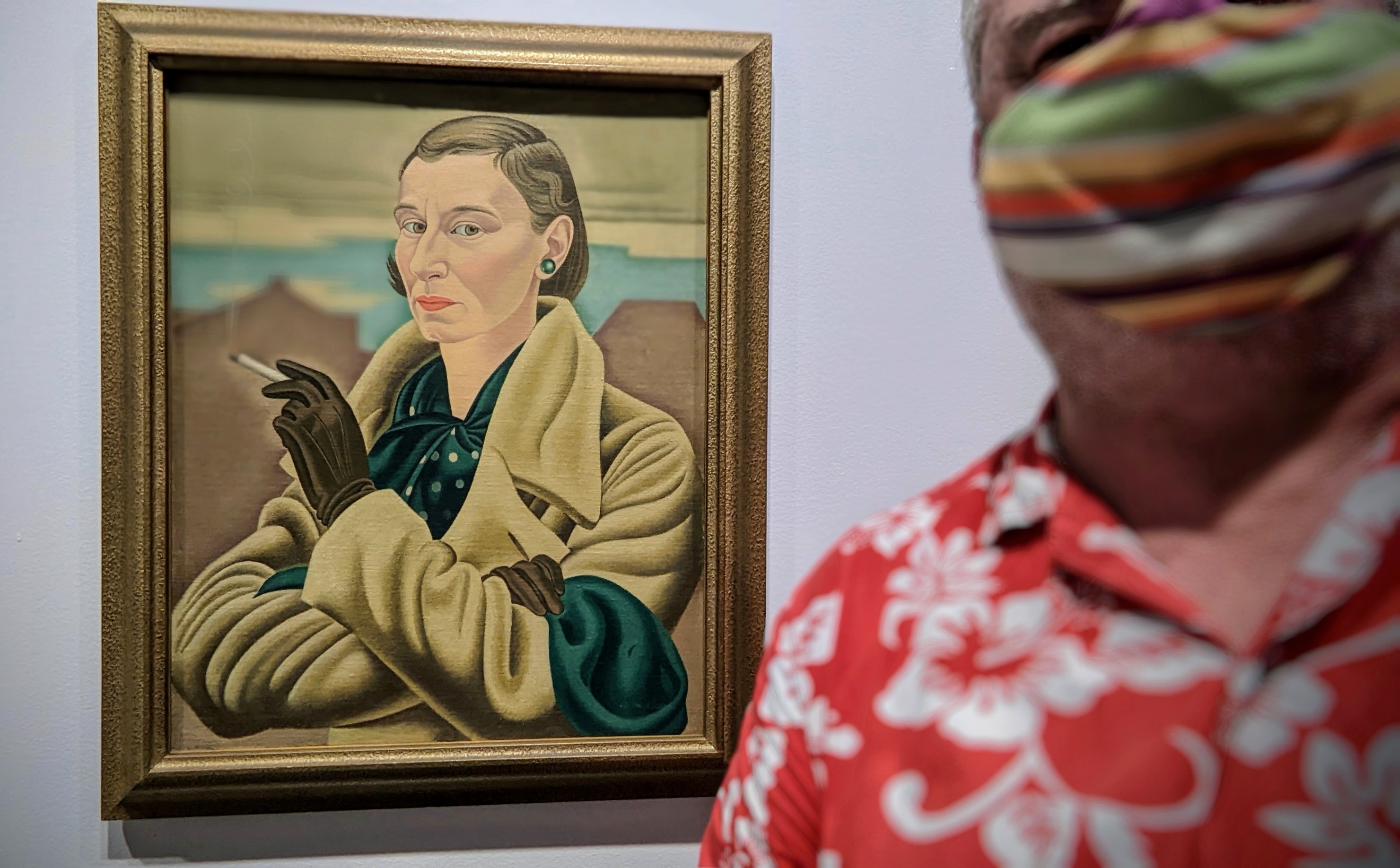 COVID masked Mike Riversdale stood near Rita Angus' painting, Self Portrait (1936-37)