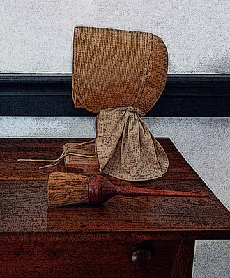 a Shaker bonnet and clothes brush rest on a side table