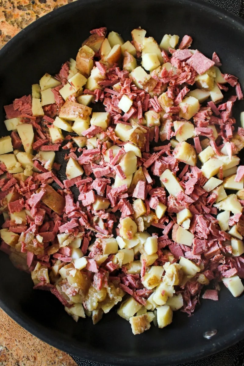 Top view of corned beef and potatoes in a frying pan.