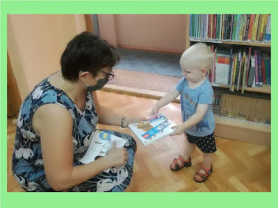 Niebieskie tło zdjęcie pani daje dziecku książkę kampanii z tygryskiem Pierwsze czytanki dla zakładkę i kartę na naklejki w tle ściany i regały z książkami