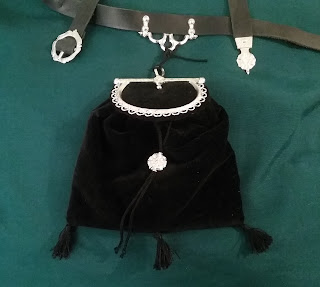 The finished purse suspended from a leather belt with pewter fittings.