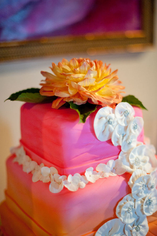 Beautiful bright orange cake set over four tiers with pink icing scrolls