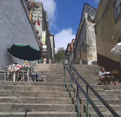 escadaria da cidade do Porto com mesinhas de restaurante e um homem sentado em uma delas
