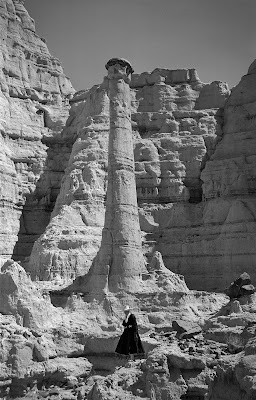 Geogia O'Keefe in New Mexico landscape by rock formation known as "smokestack"