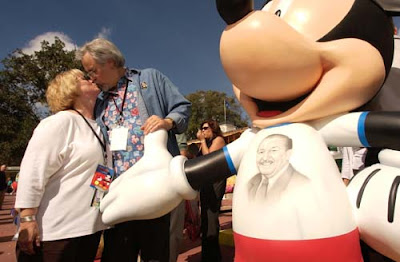 ©Disney - Russi Taylor and Wayne Allwine, the voices of Minnie Mouse and Mickey Mouse respectively, share a kiss near the InspEARations statue they designed to help celebrate Mickey and Minnie's 75th Birthday.