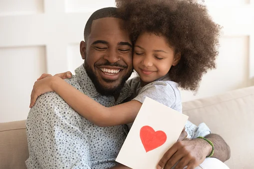 A daughter presenting greeting card to her dad