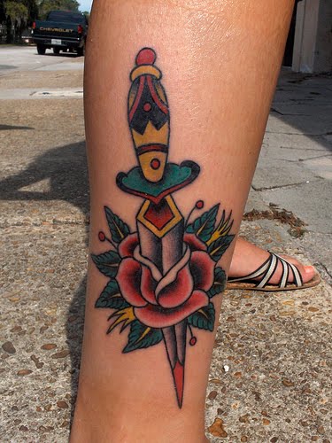 Colorful rose and dagger tattoo on lower leg.
